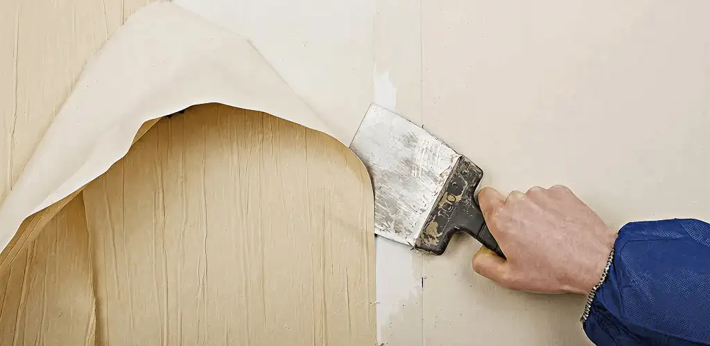 Handyman removing wallpaper with a scraper for wall preparation in Jacksonville, FL